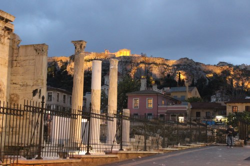 Pelas ruas de Atenas com a visão noturna da Acrópoles, no alto.